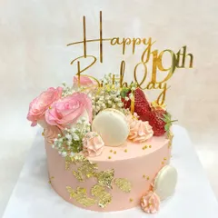 Pretty in pink! This lovely cake is decorated with fresh pink roses, strawberries, macarons, and gold leaf for a soft and romantic feel.
