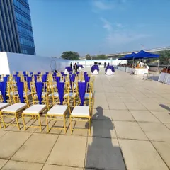 For corporate clients like Indigo Airlines, we execute professional outdoor events with precision. This rooftop setup features neatly arranged Chiavari chairs with custom blue fabric, reflecting the company's branding against a clean, urban backdrop.