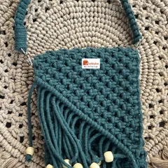 This small handbag in a lovely dark green is perfect for everyday use. It features a fringed design with wooden beads for a natural, bohemian look.