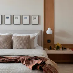 The master bedroom in the NG Penthouse is a study in simple, timeless elegance. A custom wood-panelled wall integrates the bedside lighting, while a vintage textile adds a touch of color and pattern to the serene setting.