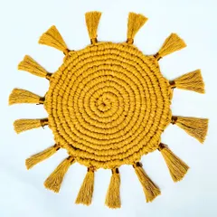 A top-down view of the mustard yellow sunburst placemat. You can see the detail of the spiral knotting in the center and the neat tassels all around. It's a beautiful piece of functional art for your table.