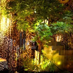 Lush greenery and warm uplighting against a backdrop of leopard-print drapery, adding a touch of the jungle to the opulent theme.