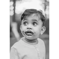 This black and white close-up of Ivaan after his cake smash is full of character. The monochrome treatment emphasizes his wide, curious eyes and the delightful chocolatey mess.