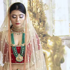 A closer look at the red velvet bridal lehenga, highlighting the deep V-neckline of the blouse and the sheer net dupatta. The richness of the velvet fabric gives the outfit a truly luxurious feel.