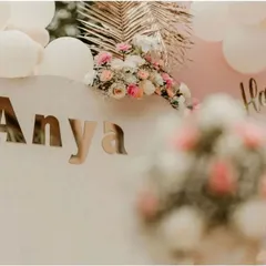 A close-up of the personalized details from a boho-chic first birthday. The elegant gold mirror lettering for the name "Anya" adds a touch of sophistication to the minimalist backdrop.
