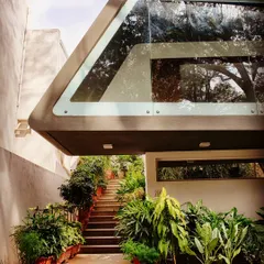 A view of the single-flight staircase leading up to the cantilevered canopy of the Mobius Home. The design uses lush greenery along the path to create a tranquil transition from the ground level.