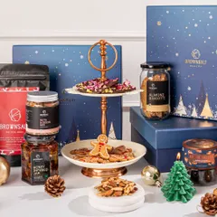 A beautiful display of our Christmas hamper collection. This tiered stand features our gingerbread cookies and rose pistachio chocolate barks, surrounded by other festive goodies like almond biscotti and our special Xmas granola.