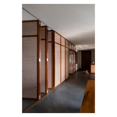 A series of pivoting teak and rattan shutters that separate different zones in a home. When open, they create a permeable screen that allows light and air to pass through; when closed, they offer privacy while adding texture to the space.