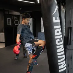 A young student practices his knee strike on the heavy bag. This drill builds power and precision, essential weapons in a Muay Thai fighter's arsenal.