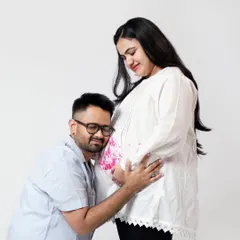 The father-to-be listens closely to the baby bump. This is a sweet and classic pose for any pregnancy announcement or maternity photoshoot.