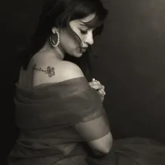 There is a unique power in monochrome. By stripping away color, we focus on the raw emotion, the subtle play of light on skin, and the story told in a single glance. This portrait captures a moment of quiet introspection, highlighting the delicate tattoo as a personal mark of her journey.