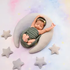 A classic "over the moon" shot with a newborn stretching out on a crescent moon prop, surrounded by soft stars. This whimsical theme is a favorite for celebrating your new little star.