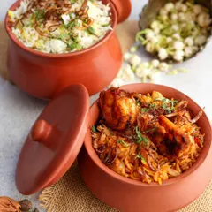 Aromatic prawn and vegetable biryanis served in traditional clay handis, styled with fresh jasmine flowers for an authentic touch.