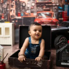 A smile that could fix anything. This little guy is having a blast in his garage-themed photoshoot, a great way to capture a boy's playful spirit.