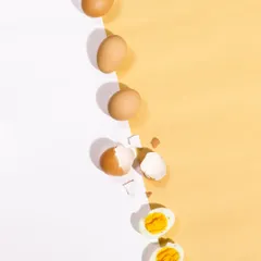 A creative and conceptual shot showing the journey of an egg from whole to boiled. The strong diagonal line and hard light create a modern, graphic look that is perfect for social media and advertising.