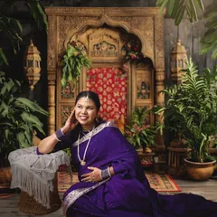 Celebrate your heritage with a traditional maternity photoshoot. This portrait, inspired by classic Indian artistry, features a rich purple saree and an ornate, traditional backdrop, creating a timeless and culturally significant memory.