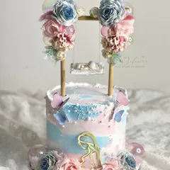A beautiful gender reveal swing cake with a mix of pink and blue flowers. The swing structure is versatile and can be customized for any theme.