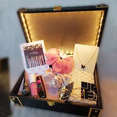 A trunk box hamper curated just for her. This one is filled with accessories like a butterfly necklace, hoop earrings, scrunchies, and makeup, all revealed by glowing fairy lights.