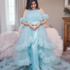 A client makes a heart shape over her baby bump in our sky blue tiered maternity gown. The long trail spreads out beautifully for seated poses.