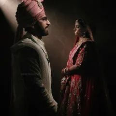 A similar dramatic wedding portrait with a slightly different angle, emphasizing the rich colors of the bride's attire against the dark background.