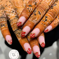 Perfect for a bride, these nails feature a modern French design with hand-painted red and gold heart-shaped tips, beautifully complementing the intricate henna.