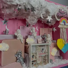 A wider view of the 'little angel' hamper, showing the personalized name sign, rainbow macrame, and the arrangement of gifts that create a whimsical sky scene.