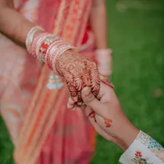 A close-up shot of the couple holding hands after the ring exchange, highlighting the bride's intricate henna and the new rings. This detail shot is a beautiful part of the engagement story.