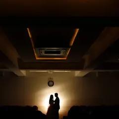 We love creating grand, cinematic moments. By using a single light source to create a silhouette, we turned this couple's portrait into a powerful, movie-like scene, emphasizing their connection against the architectural lines of the hall.