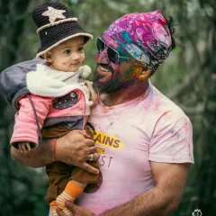 A heartwarming moment of connection between a father and son, sharing a look amidst the Holi colors. These are the candid, emotional shots that become treasured family memories.