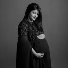 A gentle and introspective black and white portrait of the mom-to-be looking down at her bump.