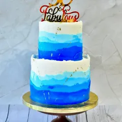 A cake to celebrate being "50 & Fabulous." This two-tier design features a beautiful blue ombre watercolor effect, accented with flecks of gold leaf for a touch of modern elegance.