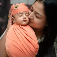 A mother’s gentle kiss for her sleeping newborn. Our specialized newborn sessions focus on creating these quiet, precious moments, using soft wraps and props to ensure your baby is safe and comfortable.
