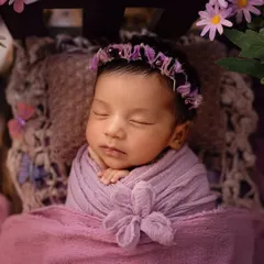 A sleeping newborn in a dreamy, butterfly-themed setup. The soft purple tones and delicate props create a magical and serene portrait.