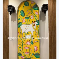 This Pichwai mural, framed by a beautiful archway, serves as a stunning welcome in a foyer. The bright yellow background makes the traditional cow and lotus motifs pop with energy.