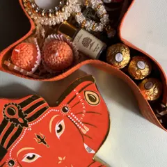 A close-up view of the contents, showing the motichoor laddoos, chocolates, and a small bottle of perfume nestled inside.