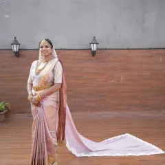 A stunning full-length portrait of a South Indian bride, showcasing her elegant Kanjivaram saree with a long, modern train.