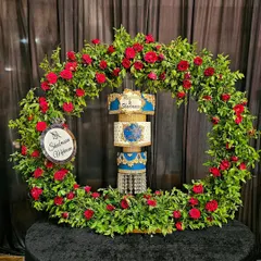 The magnificent chandelier cake in its full glory, framed by a beautiful arch of red roses. A true statement piece for a grand engagement or wedding.