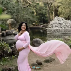 This mom-to-be looks like a princess in her pink gown, set against the beautiful backdrop of a park pond. The flowing train of the dress adds a touch of drama and elegance to this outdoor portrait.