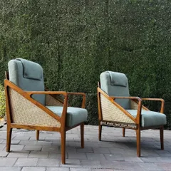 A pair of high-back lounge chairs combining a solid wood frame with cane side panels and a comfortable, adjustable headrest.