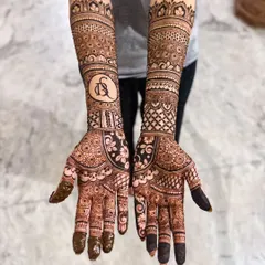 This bridal design combines traditional patterns with a personalized touch. A custom monogram with the couple's initials, D and S, is featured prominently on the forearm.