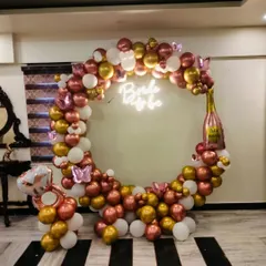 This elegant indoor balloon ring is perfect for a bride-to-be celebration. The combination of metallic rose gold, gold, and white balloons, along with a champagne bottle foil balloon, creates a chic and festive photo corner.