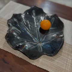 The finished leaf platter, styled on a simple table runner. The deep, flowing glazes catch the light, highlighting the intricate veins of the leaf and turning a natural object into a lasting piece of ceramic home decor.