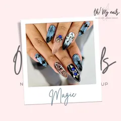 Dark and dreamy cat eye nails. This artistic set uses a magnetic polish to create a deep, shifting pattern, accented with intricate line work and bold blue crystals.
