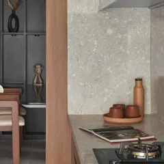 This view shows the kitchen's connection to the dining area, highlighting the open and social feel of the apartment. The terracotta and wood tones create a warm and inviting transition.