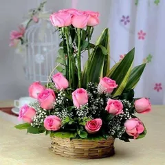 This two-tiered pink rose basket is a beautiful alternative to a standard bouquet. The arrangement is designed to be displayed on a table, making it a lovely gift for a home or office.