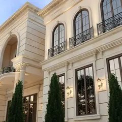 An upward view of the facade, highlighting the detailed cornices, arched windows, and wrought-iron balcony railings.