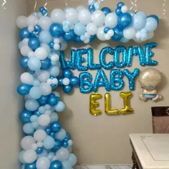 This detailed shot shows the organic balloon garland we created for baby Eli's welcome home party. The mix of different sized balloons in metallic blue, pastel blue, and white adds texture and depth to the overall design.