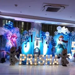 A complete Frozen-themed birthday party setup for Prisha's 5th birthday. The scene includes character standees, an ice castle, marquee letters spelling the name, and plenty of blue, white, and silver balloons to create a winter wonderland.
