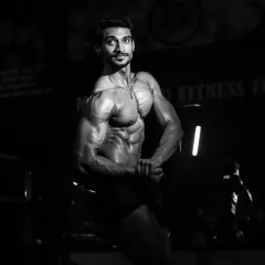 A black and white shot from a competition, focusing on the side chest pose. This highlights the muscle definition and conditioning needed to compete at a high level.