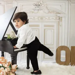 A playful shot of a one-year-old boy trying to play the piano. Our milestone sessions are all about capturing the curious and fun-loving nature of toddlers.